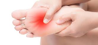 A person touches his foot and notices red patches on it, suggesting pain.